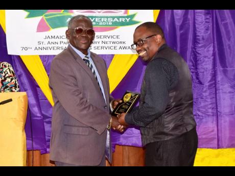 Fabian Smith (right) collects his plaque from Radcliffe Walters, chairman, St Ann Parish Library network.