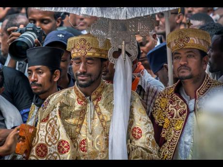 A priest cries at a mass funeral at the Holy Trinity Cathedral in Addis Ababa, Ethiopia, yesterday. Thousands of Ethiopians turned out to a mass funeral in the capital one week after the Ethiopian Airlines plane crash. Officials have begun delivering bags of earth to family members of the 157 victims of the crash, instead of the remains of their loved ones, because the identification process is going to take such a long time. 