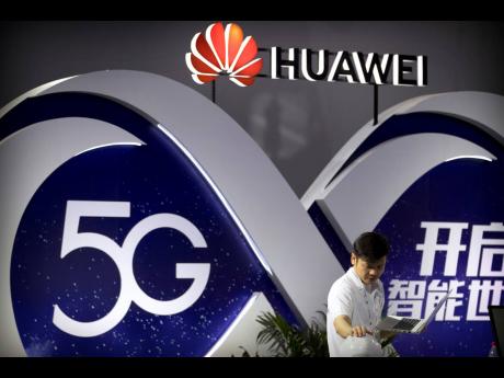 In this 2018 photo, a staff member uses a laptop at a display for 5G wireless technology from Chinese technology firm Huawei at the PT Expo in Beijing. 