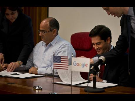 Google’s head of Cuba operations, Brett Perlmutter, right, signs a deal with Luis Adolfo Iglesias Reyes, vice president of investments of Etecsa, left, in Havana, Cuba, yesterday. 