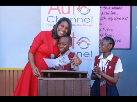 Head boy Jordan Easington receives a hug from Kerine Hamilton, marketing and planning  director Auto Channel Limited after showing his appreciation of the donation of a washing machine to his school.  Looking on is head girl Jhanae Stewart. 

