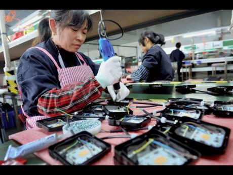 In this Saturday, March 30 photo, workers assemble LED lights at a factory in Yushan county in central China’s Jiangxi province. 