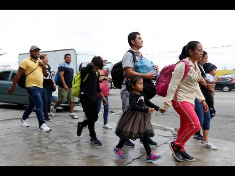 Migrants walk along a highway as a new caravan of several hundred people sets off in hopes of reaching the distant United States, in San Pedro Sula, Honduras, shortly after dawn yesterday. 