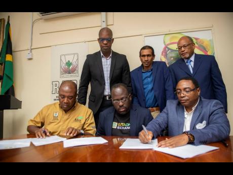 (From left, foreground) CEO of RADA Peter Thompson; Robert Thompson, director, CNET-OUTAONE; Clarence Hill, vice-president of operations, OUTAONE; (from left, background) Robert Miller, senior adviser to J.C. Hutchinson, minister without portfolio; Nigel Myrie, chairman, RADA; and Errol Bailey, co-founder, OUTAONE, participate in the signing of two memoranda of understanding at the RADA office in St Andrew on Wednesday. 