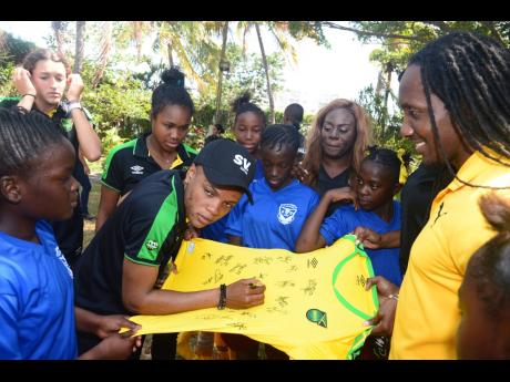 
Reggae Girl Trudy Carter signs an official Reggae Girlz jersey for the Greenwich All-Age football team during a social outreach event organised by Supreme Ventures on May 17 – Child’s Day. The event was the final send-off for the Reggae Girlz from Supreme Ventures before their departure for France and the FIFA Women’s World Cup.