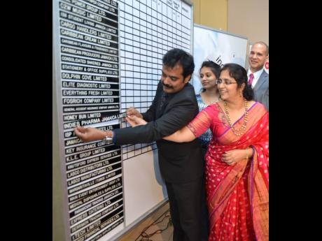 Guna Muppuri (left) and Vishu Muppri insert the Indies Pharma strip on the listing board of the Jamaica Stock Exchange in August 2018.