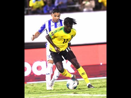 Jamaica’s Shamar Nicholson (front) dribbles ahead of Honduran player Emilio Izaguirre in their Group C Concacaf Gold Cup match at the National Stadium on Monday night. 