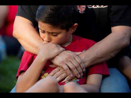 Robbie Ramirez, 10, holds on to his father, Robert Ramirez, during a vigil for victims of a Sunday evening shooting that left three people dead at the Gilroy Garlic Festival on Monday, July 29, in Gilroy, California. 