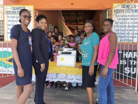 The teaching team and students at the Beersheba Primary School in St Elizabeth were all smiles as they received a donation of a printer valued at J$140,000 from NCB Foundation. The gift is expected to improve the learning environment for the school as they head into exam preparation mode in the next school term. From left are: Donique Bucknor, NCB Black River lobby officer; Mary Singh, NCB Black River service quality manager; Principal Michelle Sanderson and Cara Stone Martin, teacher .