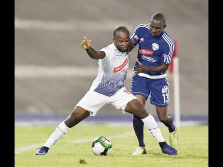 Credit: Gladstone Taylor Javon East (left), representing Portmore United, keeps Xavian Virgo of Mount Pleasant away from the ball in the Red Stripe Premier League semi-final at the The National Stadium on Monday, April 15.