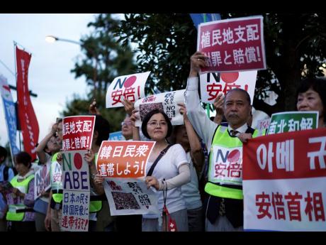 AP 
A group of protesters gather outside Japanese Prime Minister Shinzo Abe’s residence in Tokyo Thursday, August 8. They staged a rally with placards to urge the government to apologize for wartime atrocities in an effort fix rapidly souring relations. 