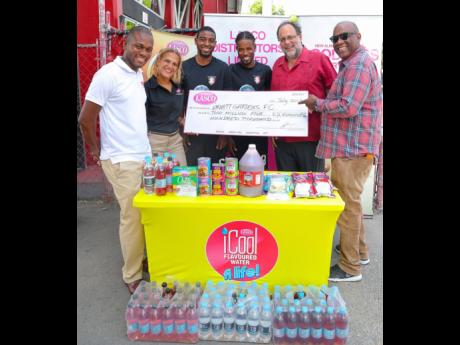 From left: LASCO Distributors Limited Marketing Manager Omar Palmer and Beverage Marketing Manager Danielle Cunningham present a $2.5-million cheque to Arnett Gardens Football Club midfielder Ricardo Oldham, and defender Lamard Neil, solidifying LASCO’s support of the club’s preseason preparations, on Thursday, July 25, 2019, in Arnett Gardens. Joining the proceedings are Member of Parliament for South St Andrew and Chairman of Arnett Gardens FC Mark Golding and the club’s general manager, Peter Thelwell.  