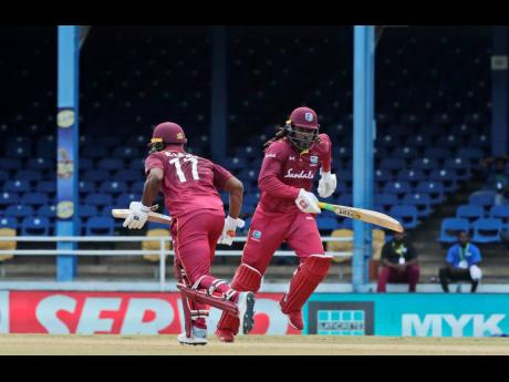 West Indies opening batsmen Evin Lewis (left) and Chris Gayle run between the wickets during the second One-Day International cricket match against India in Port of Spain, Trinidad, yesterday. India won by 59 runs as Lewis top-scored for the West Indies with 65 runs.