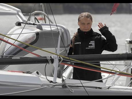 Climate change activist Greta Thunberg waves from the Malizia II boat in Plymouth, England yesterday. The 16-year-old climate change activist who has inspired student protests around the world will leave Plymouth, England, bound for New York in a high-tech but low-comfort sailboat. 