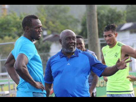 Usain Bolt (left) has a word with his coach Glen Mills during a training session at the Usain Bolt Track at the UWI Mona Bowl in 2016.