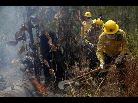 Firefighters work to put out fires in the Vila Nova Samuel region, along the road to the National Forest of Jacunda, near to the city of Porto Velho, Rondonia state, part of Brazil’s Amazon, on Sunday. 
