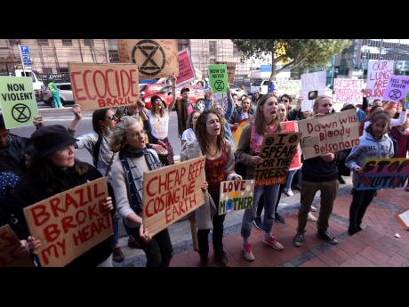 Credit: The Associated Press In this photo taken Tuesday, August 27 people hold a placard demonstration in Cape Town, South Africa, in protest against fires burning in Brazil’s Amazon rainforest. Satellite images show a far greater number of fires burning on the African continent but experts say the situation in Africa is different and not yet a growing problem attributing the abundance of fires across the savannah lands to agricultural technique by small farmers cultivating fields.