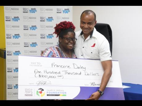 Nestlé Jamaica Supply Chain Manager Linton Johnson presents Nestlé Needs YOUth 2019 Top Summer Intern Francene Daley with a bursary cheque for $100,000.