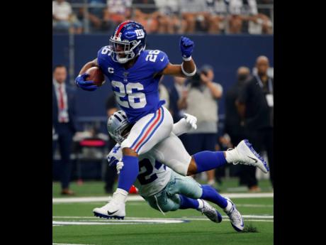 New York Giants running back Saquon Barkley (front) attempts to escape the tackle by Dallas Cowboys cornerback Chidobe Awuzie in the first half of their NFL game in Arlington, Texas, yesterday. 