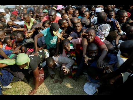 Mourners stampede after the arrival of the coffin carrying former President Robert Mugabe at the Rufaro Stadium in Harare on Thursday, September 12, where Mugabe will lie in state for a public viewing. 