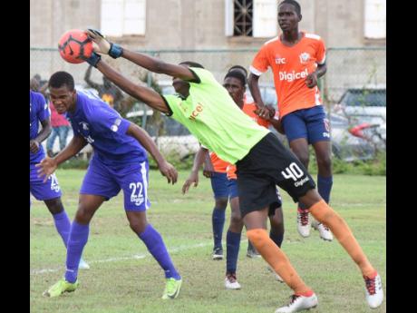 Credit: Ian Allen Dunoon Technical High School goalkeeper Ricardo Watson stretches to collect a cross into the box ahead of Kingston College’s Scott McLeod (left) during their aborted ISSA/Digicel Manning Cup game at the Breezy Castle Field in downtown Kingston yesterday.