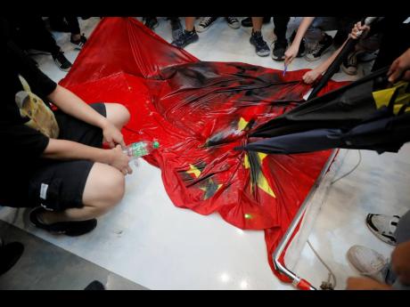 Protesters vandalize a Chinese national flag during a protest at a mall on Sunday in Hong Kong. Hong Kong’s pro-democracy protests, now in their fourth month, have often descended into violence in the evenings.  (AP)