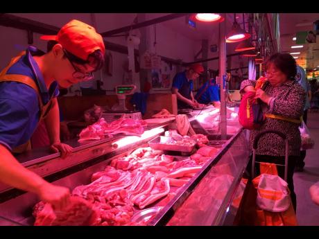AP 
In this Wednesday, September 11, 2019 file photo, a clerk stacks cuts of pork at a meat market in Beijing. 
