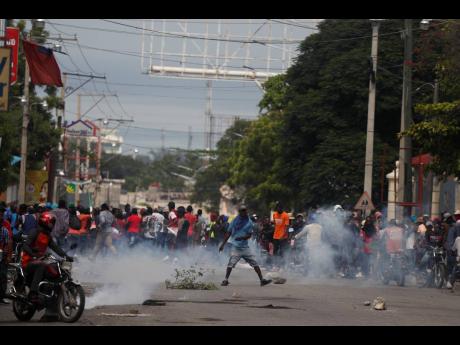 Protesters turn and run as police began to fire tear gas as they gather in Port-au-Prince, Haiti, on Monday. 