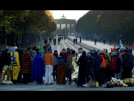 Supporters of the ‘Extinction Rebellion’ movement block a road between the Brandenburg Gate, background, and the Victory Column in Berlin, Germany, Monday, October 7. The activists want to draw attention on the climate protest by blocking roads and with other acts of civil disobedience in Berlin and other cities around the world.