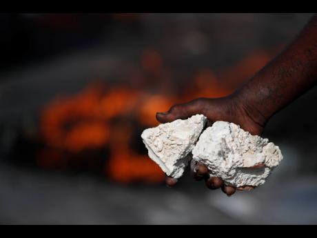 A protestor holds rocks while walking in front of burning tires at a barricade as protesters seek to paralyse transport and commerce in order to pressure President Jovenel Moïse to resign in Port-au-Prince, Haiti, on Tuesday.