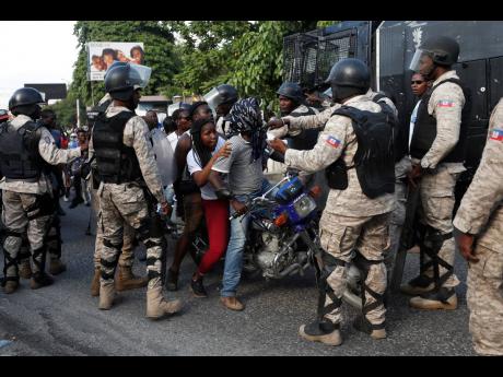 Police surround a motorcycle that tried to drive through a police barricade on the road leading to the home of President Jovenel Moïse in Petion-Ville, Port-au-Prince, Haiti, on Sunday.  AP