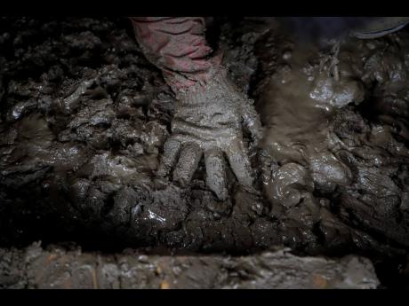 Yoshiki Yoshimura, 17, sifts through the mud for anything salvageable at his home destroyed by Typhoon Hagibis Tuesday, Oct. 15, 2019, in Nagano, Japan. More victims and more damage have been found in typhoon-hit areas of central and northern Japan, where rescue crews are searching for people still missing. (AP Photo/Jae C. Hong)