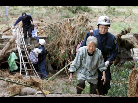 Residents are helped to walk through a road blocked by debris caused by Typhhon Hagibis, to head to a shelter in Koriyama, Fukushima prefecture, Japan Tuesday, Oct. 15, 2019. More victims and more damage have been found in Typhoon Hagibis-hit areas of central and northern Japan, where rescue crews are searching for people still missing. (Kota Endo/Kyodo News via AP)