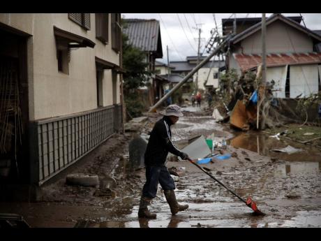 A man cleans up mud in a neighborhood destroyed by Typhoon Hagibis Tuesday, Oct. 15, 2019, in Nagano, Japan. More victims and damage have been found in typhoon-hit areas of central and northern Japan, where rescue crews are searching for people still missing. (AP Photo/Jae C. Hong)