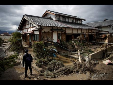 A man surveys a home damaged by Typhoon Hagibis Tuesday, Oct. 15, 2019, in Nagano, Japan. More victims and more damage have been found in typhoon-hit areas of central and northern Japan, where rescue crews are searching for people still missing. (AP Photo/Jae C. Hong)