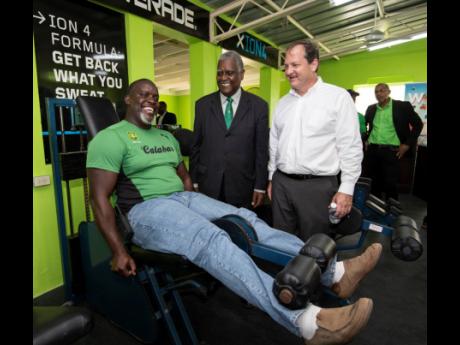 Dr Vincent Lawrence (centre) and François Chalifour (director of marketing and IT, Wisynco) look on as Julian Robinson (old boy and renowned coach) checks out the equipment in the newly opened Vincent Lawrence Gymnasium at the Calabar Sports Complex yesterday on the school compound.