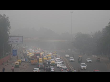 In this Sunday, Nov. 3, 2019, photo, vehicles wait for a signal at a crossing as the city enveloped in smog in New Delhi, India. Authorities in New Delhi are restricting the use of private vehicles on the roads under an “odd-even” scheme based on license plates to control vehicular pollution as the national capital continues to gasp under toxic smog. (AP Photo/Manish Swarup)