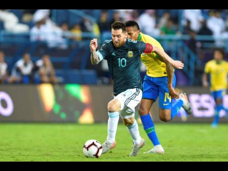 Argentina’s Lionel Messi (front) dribbles by Brazil’s Militao during a friendly international match at King Fahd Stadium in Riyadh, Saudi Arabia, on Friday. 