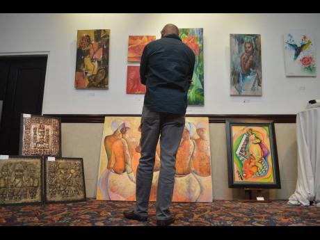 Credit: Contributed A guest admires works of Jamaican artists at Osmosis Caribbean’s ArtBeats #Live showcase last year.