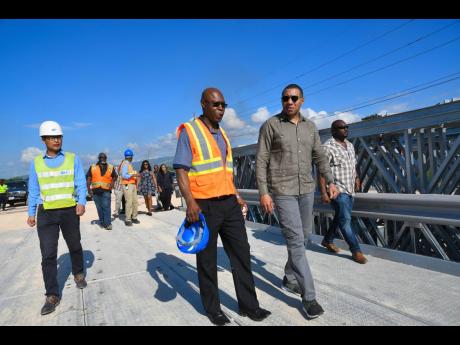 Credit: File Prime Minister Andrew Holness (second right), National Works Agency CEO E.G. Hunter, (centre) and He Jiany Bo, project manager of China Harbour Engeneering Company, observing work on the legacy road project in the vicinity of Portia Simpson Miller square in November 2018.