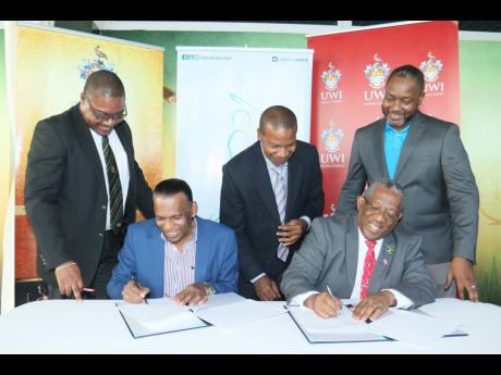 Credit: Andre Lowe Jamaica Cricket Association (JCA) President Wilford ‘Billy’ Heaven (second left) and UWI Mona Principal Prof. Dale Webber (second right) sign a memorandum of understanding between the organisations at the Faculty of Sport at the UWI. Witnessing are (from left) JCA CEO Courtney Francis, UWI, Mona campus lawyer Carl Lawrence, and JCA’s Business Development Manager, Garth Williams.