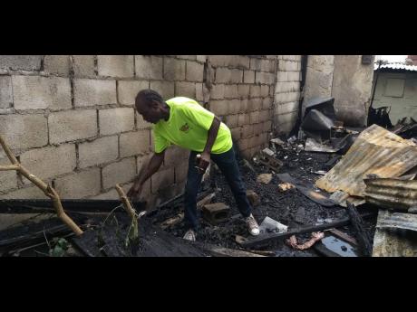 Donovan Richards sifts through the charred reamins of his home yesterday.