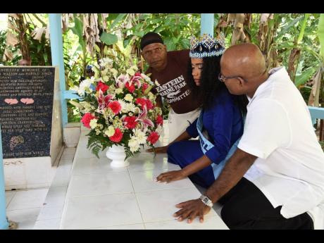 Miss World Toni-Ann Singh (centre) is assisted by her father, Bradshaw Singh (right), and uncle, Alfred Singh, as she places a wreath at the tombs of her paternal grandparents in Arcadia, St Thomas.