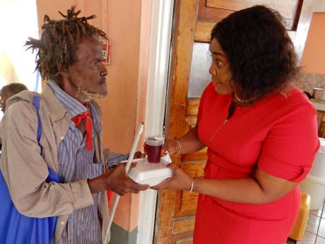 Credit: Carl Gilchrist photo This gentleman listens intently as C&WJ Regional Operations Manager Andrea Mumby offers some kind words during the credit union’s treat for street people in St Ann’s Bay on Christmas Eve.