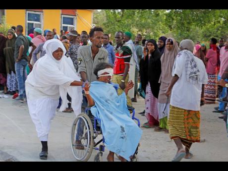 AP
A civilian who was wounded in suicide car bomb attack is helped to be taken to hospital in Mogadishu, Somalia, yesterday. A police officer says a car bomb has detonated at a security checkpoint during the morning rush hour in Somalia’s capital. 