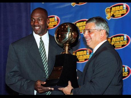 In this June 18, 1996, file photo, Chicago Bulls’ Michael Jordan (left) receives the NBA Finals Most Valuable Player trophy from Commissioner David Stern during a ceremony in Chicago. David Stern, who spent 30 years as the NBA’s longest-serving commissioner and oversaw its growth into a global power, has died on New Year’s Day, Wednesday, Jan. 1, 2020. He was 77.