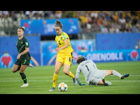 Jamaican midfielder Havana Solaun (centre) beats Australia’s goalkeeper Lydia Williams (on ground) before scoring in Jamaica’s 4-1 defeat to Australia at the 2019 FIFA Women’s World Cup at the Stade des Alpes in Grenoble, France, on June 18, 2019.