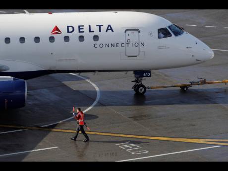 In this February 5, 2019, file photo a ramp worker guides a Delta Air Lines plane at Seattle-Tacoma International Airport in Seattle. 