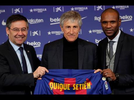 Football coach Quique Setien (centre) poses with FC Barcelona’s President Josep Maria Bartomeu (left) and director of football Eric Abidal, while being officially introduced as the club’s new coach at the Camp Nou stadium in Barcelona, Spain, yesterday. Barcelona made a rare coaching change midway through the season, replacing Ernesto Valverde with former Real Betis manager Quique Setien on Monday.