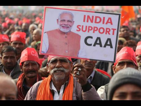 Credit: AP A supporter of India’s Bharatiya Janata party holds a banner in support of new citizenship law with the photograph of Indian Prime Minister Narendra Modi during a rally in Lucknow, India, Tuesday, January 21, 2020.